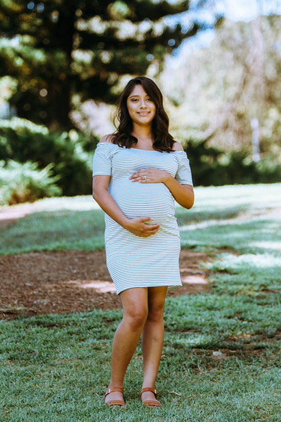 Pregnant woman standing outdoors in a white dress
