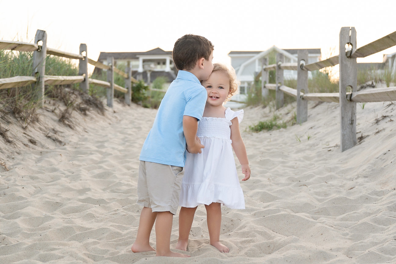 Sweet sibling kiss captured during a beach portrait session