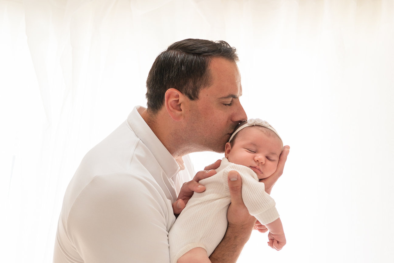Natural light lifestyle image of father looking down at sleeping newborn in Sea Girt, NJ