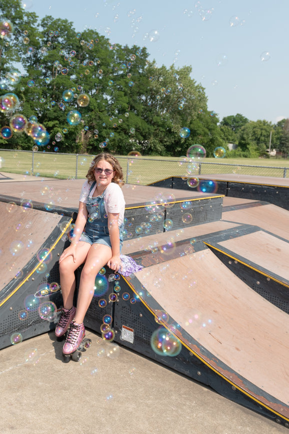 Girl sitting in a skate park with bubbles surrounding her