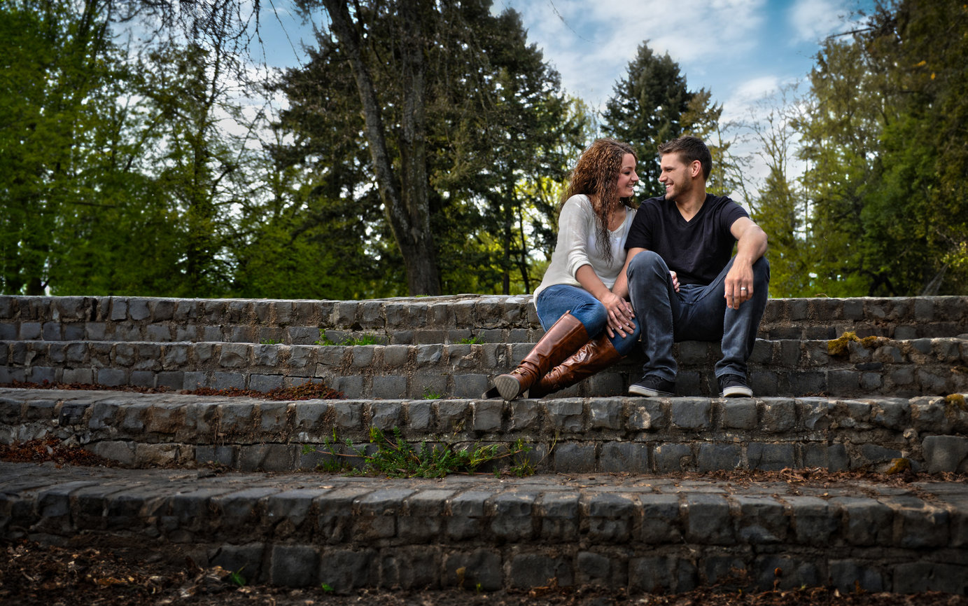 Couple sitting together on stone steps in a park.