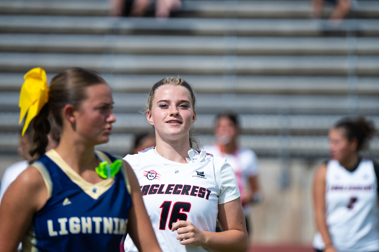 Two female athletes talking on the sidelines before a football game.