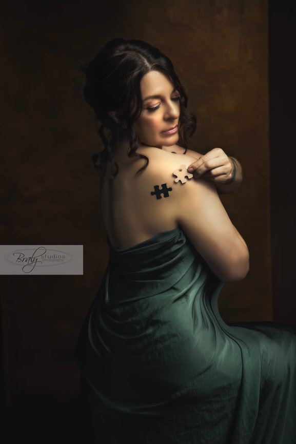 Elegant Fort Worth portrait of woman in green draped gown with black floral detail on shoulder.