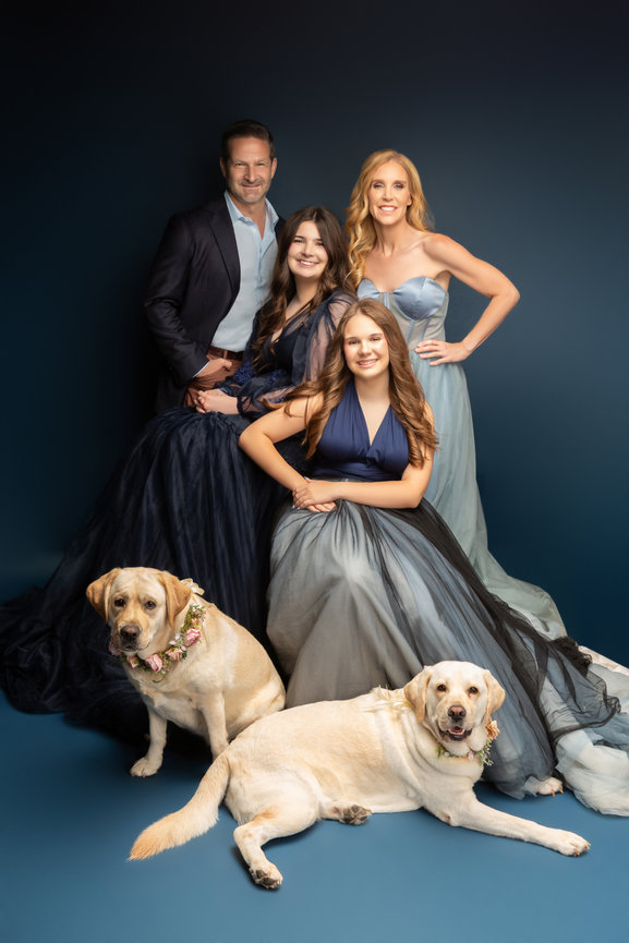 Fort Worth family portrait session with elegant gowns and two golden retrievers in studio.