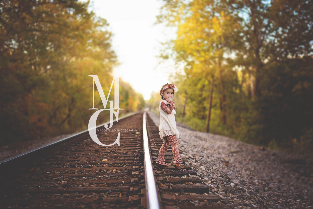 Young woman standing on railroad tracks in autumn light