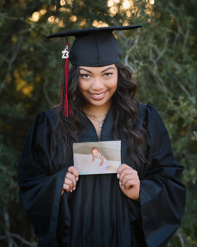 Senior girl holding a framed portrait in desert landscape
