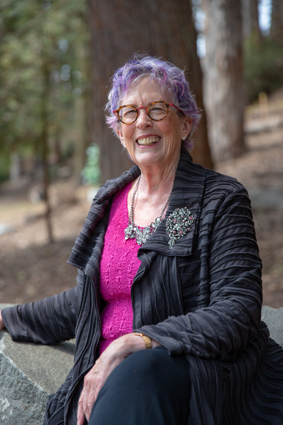Professional headshot of San Francisco woman sitting on a bench with a park landscape in the background.