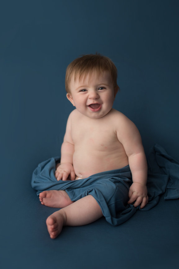 happy baby sitting on royal blue backdrop during baby photoshoot with Kansas City baby photographer Dreamworks Photography