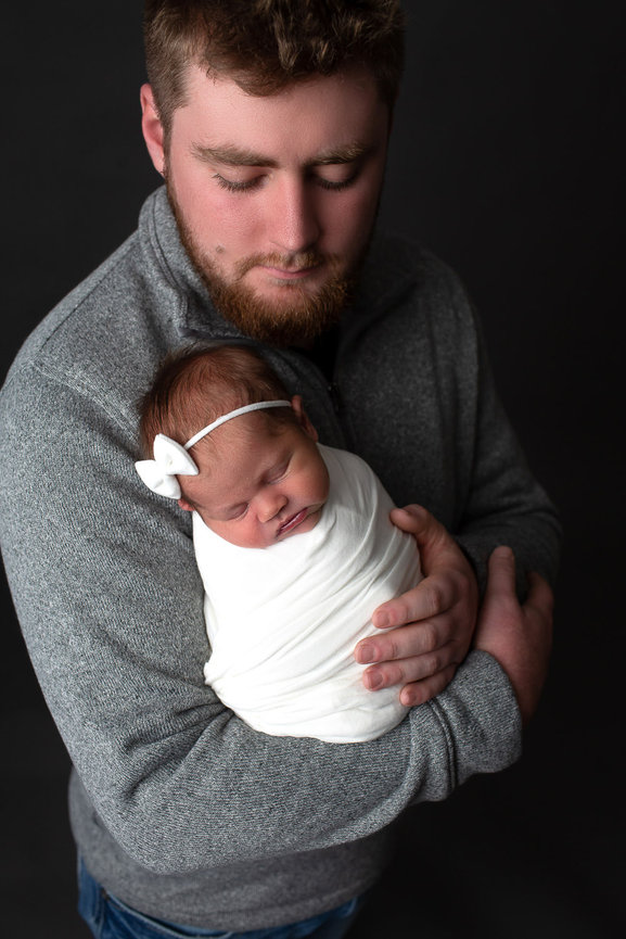 Newborn baby girl being held by her dad during newborn photography session with Kansas City's best newborn photographer Dreamworks Photography 
