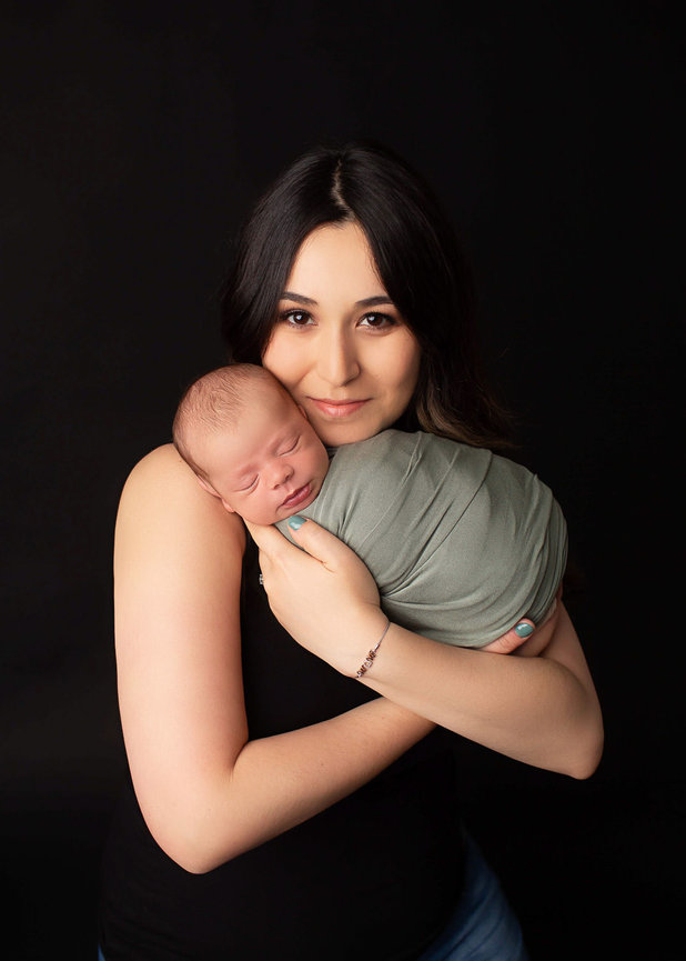 Newborn baby boy sleeping being cradled by mom during photo session durning with Kansas City newborn photographer Dreamworks Photography. 
