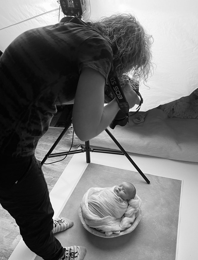 Omaha Photographer capturing a newborn wrapped in a cozy blanket, positioned in a bowl. Black and white setting.