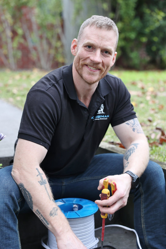Smiling technician holding tools and cable spool outdoors. tradie headshots for website