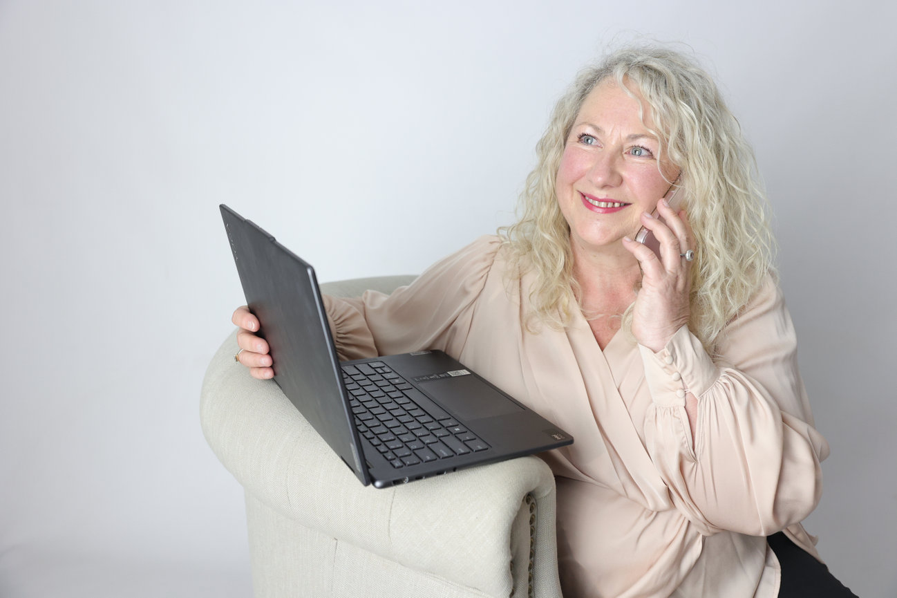 Smiling woman with laptop talking on smartphone in a bright home office. melbourne website photographer