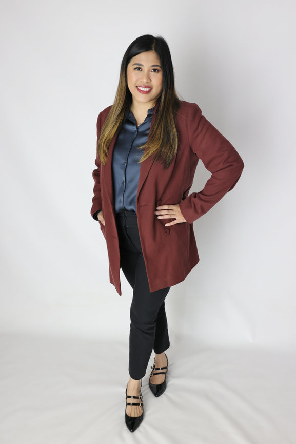 Woman posing in a burgundy blazer, navy shirt, black pants, and heels against a white background. authentic photos for my business and website