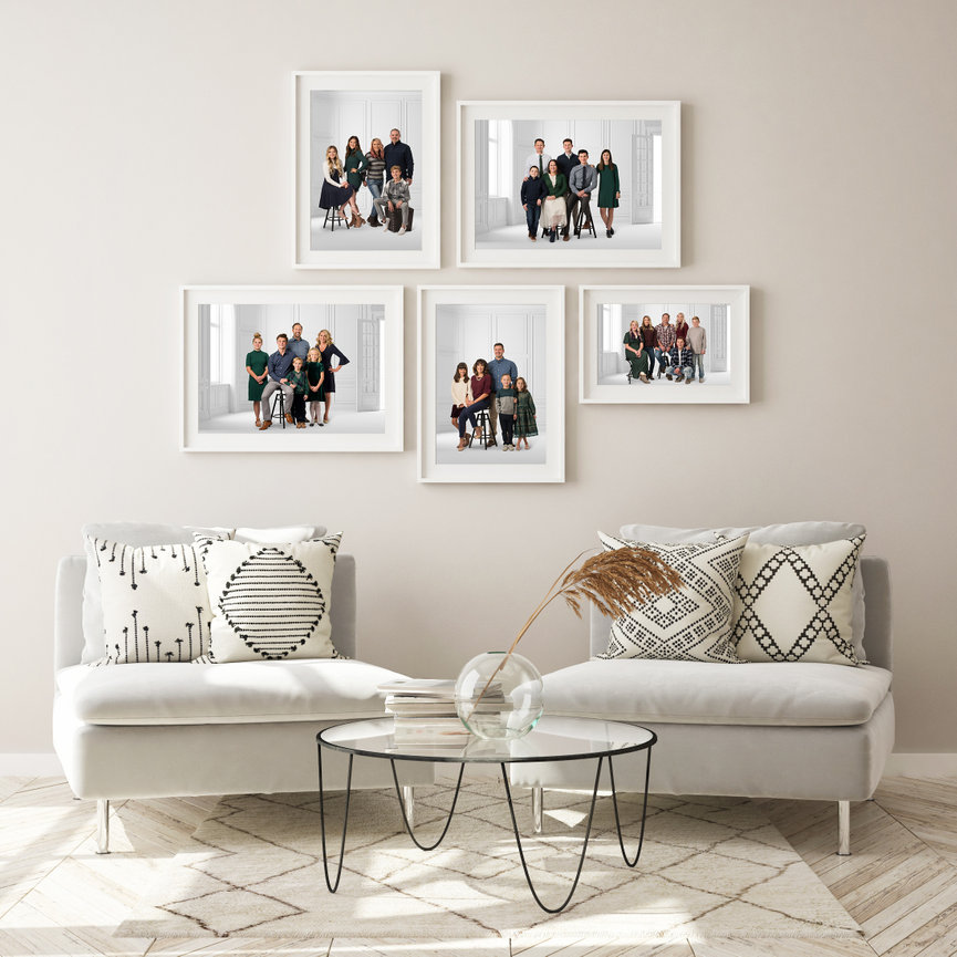 Two chairs with 5 framed portraits hanging on the wall.