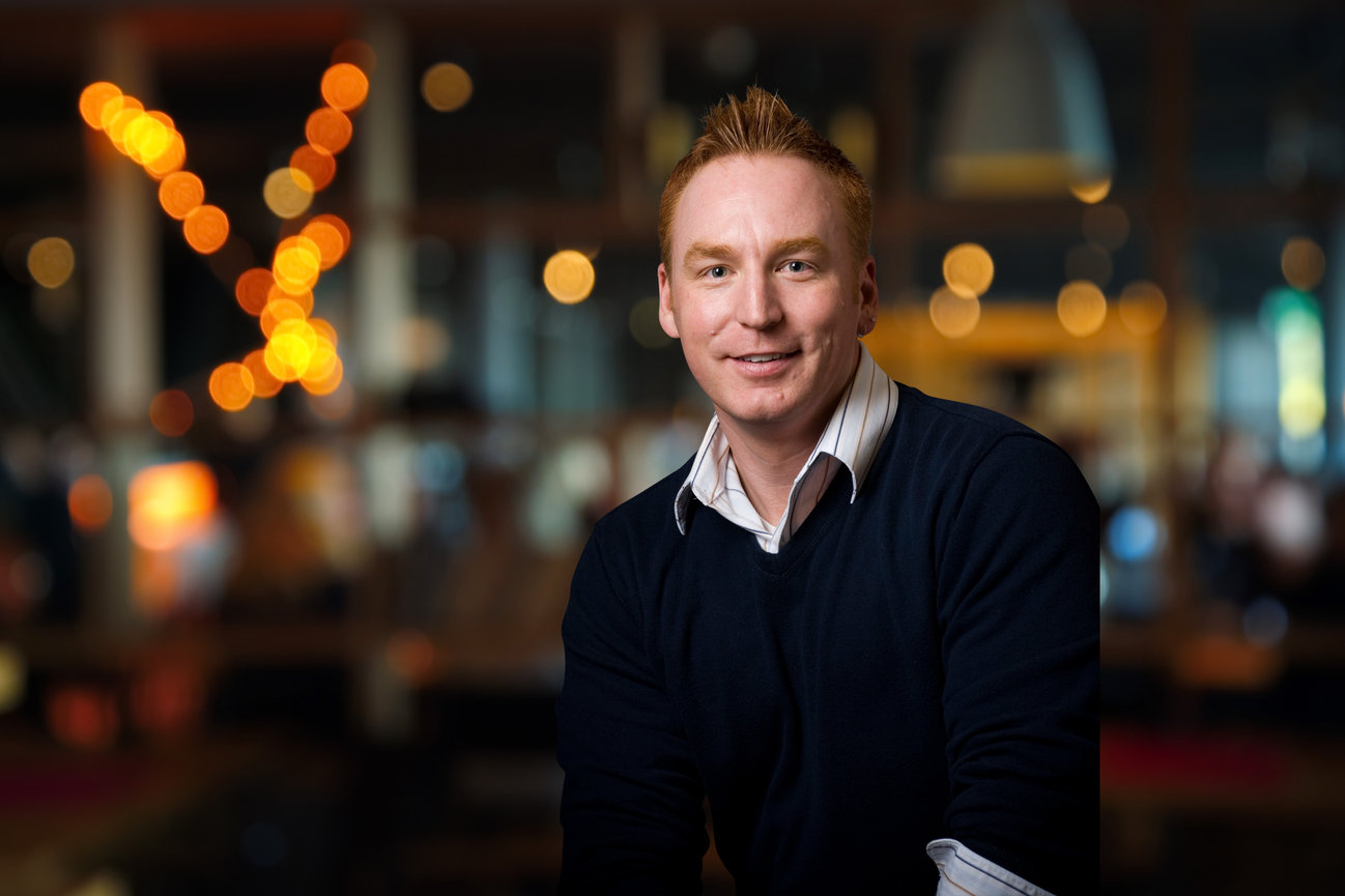 Man in a sweater posing for a headshot in a Salt Lake City restaurant for photoshoot.
