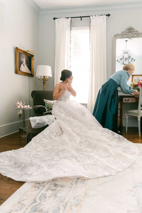 Alabama bride in custom wedding gown getting dressed in bedroom with her mom in custom dress. Luxury wedding photography by Heather Durham.