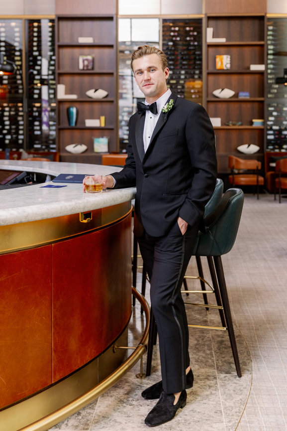 Groom standing at sophisticated Conrad Nashville hotel bar drinking an Old Fashioned. Nashville luxury wedding photography by Heather Durham.