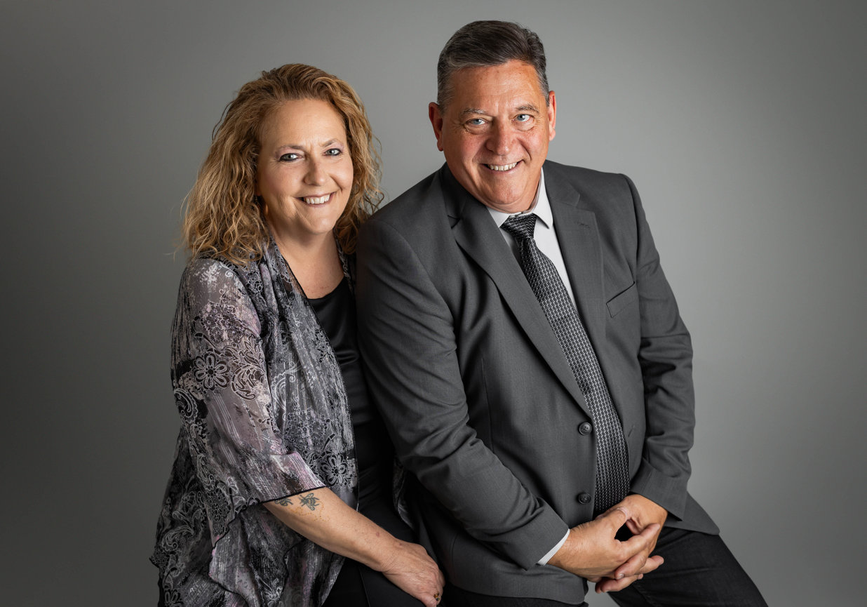Professional business headshot of man and woman smiling in studio with neutral background