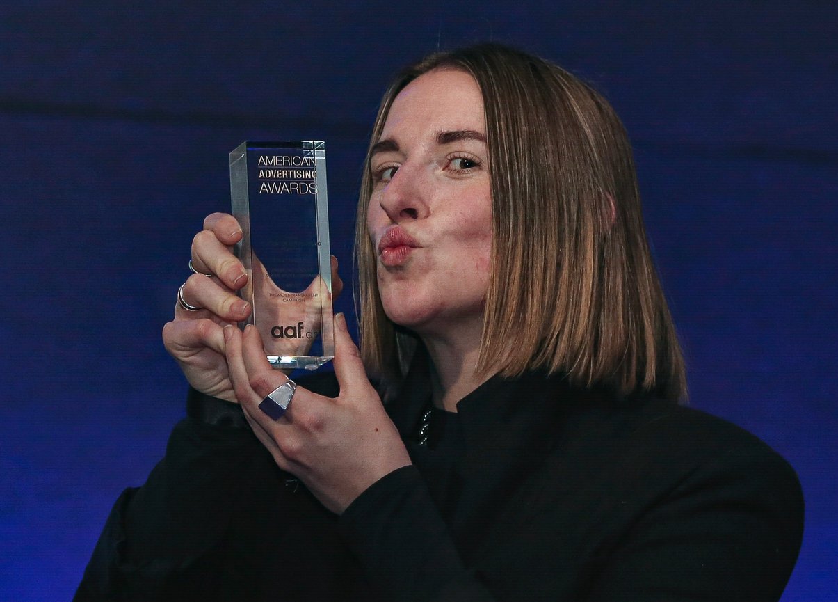 Person holding an American Advertising Awards trophy, posing with a kiss gesture.