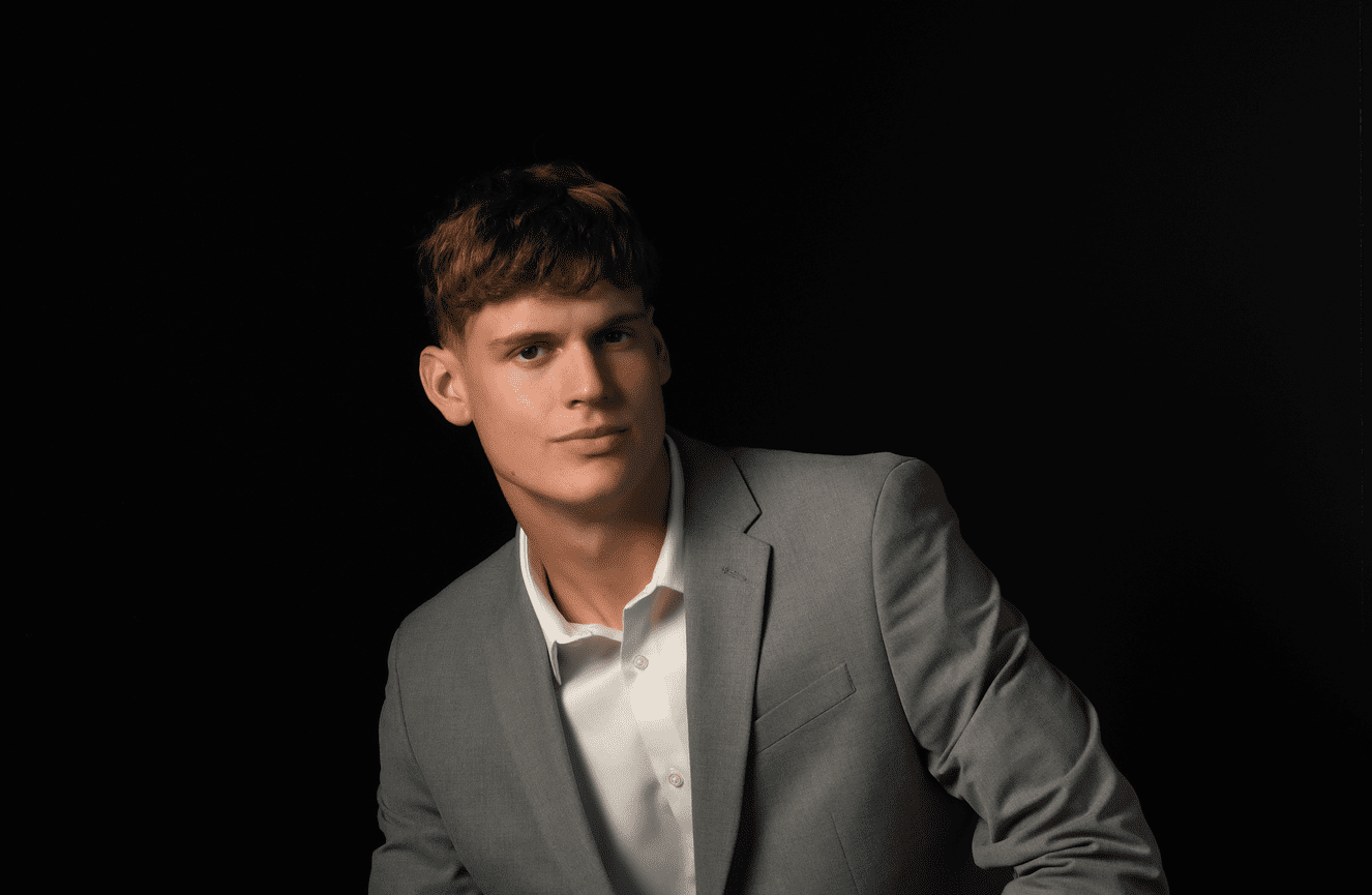 Bennett wearing a well tailored gray suit and button down white shirt in his senior photo session at Kliks Photography.