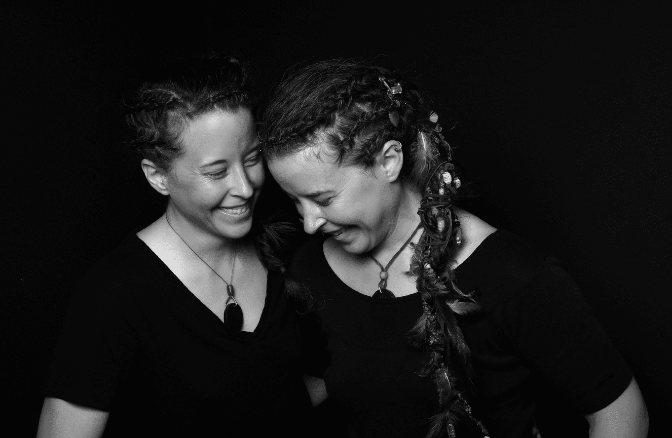 A black and white portrait of twin sisters in dreadlock hair and custom made jewelry at Kliks Photography.