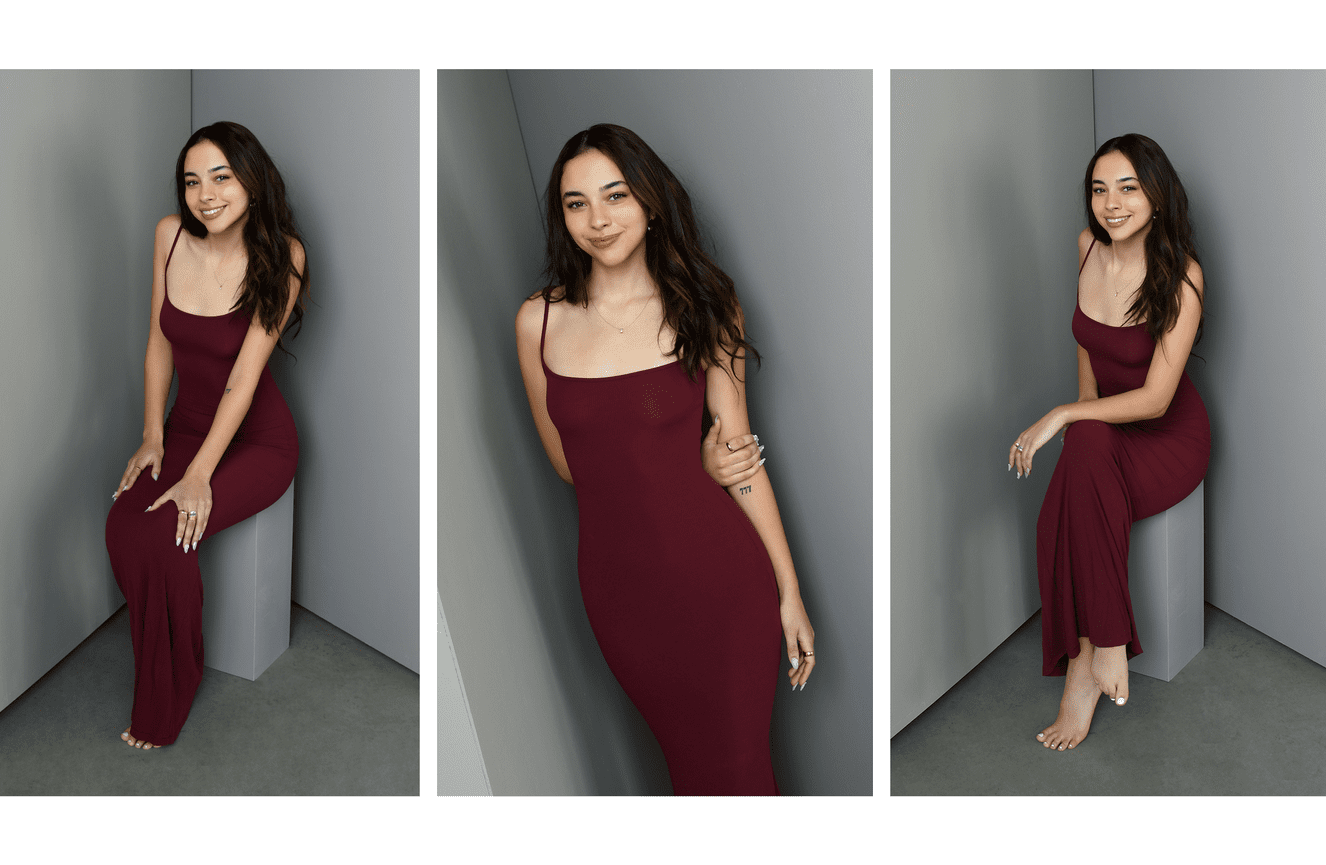 A young woman in a maroon slip dress poses for her senior photos at Kliks Photography.