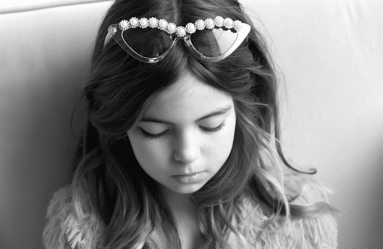 A young girl in fur and bedazzled sunglasses at Kliks Photography.