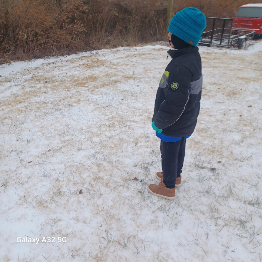 Child in a winter jacket standing in snow-covered field