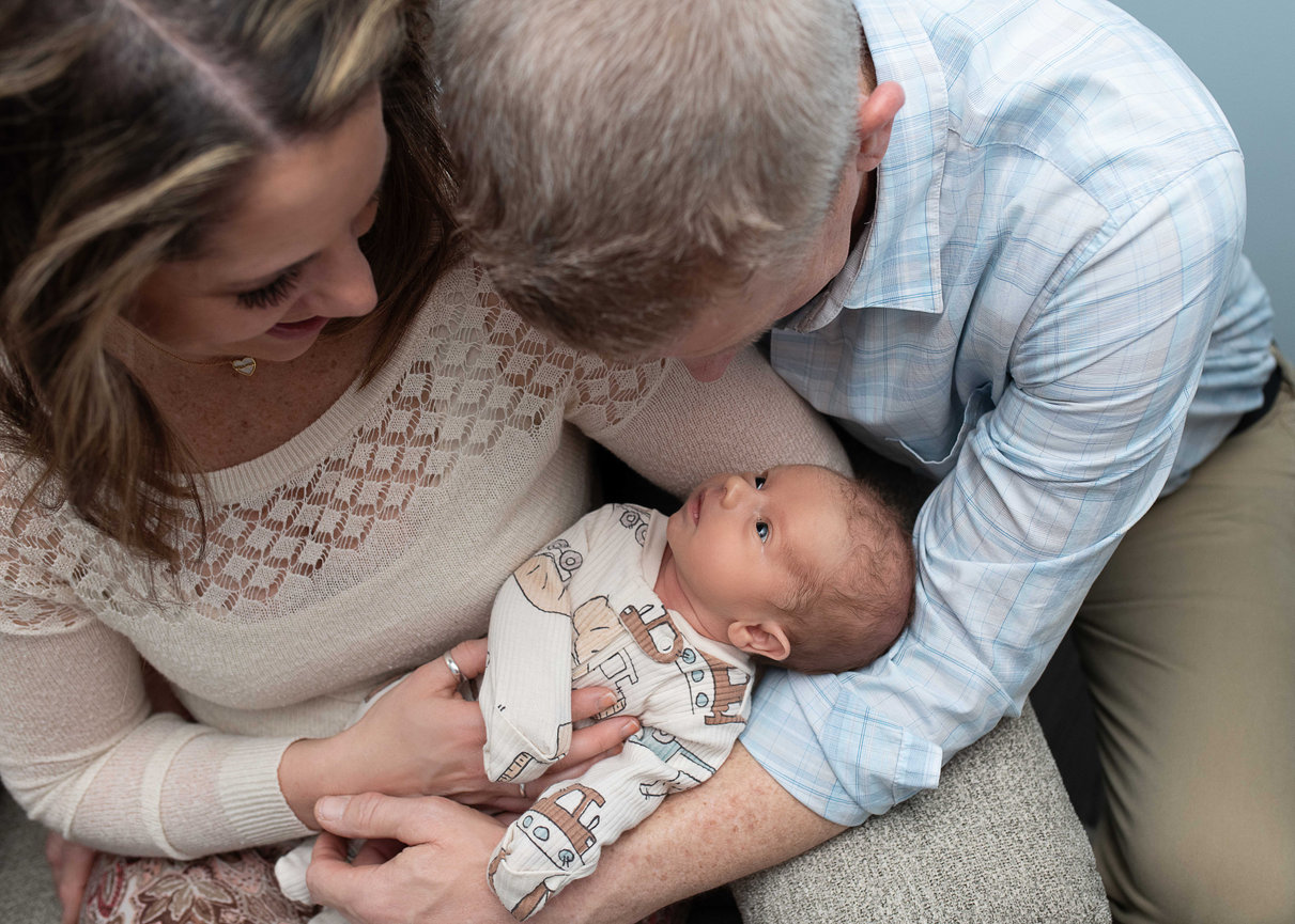 Parents lovingly hold and gaze at their newborn baby.