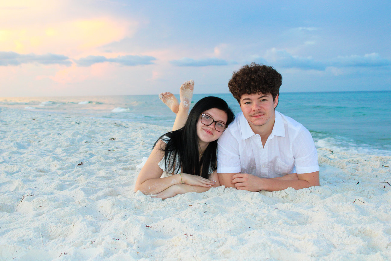 A smiling couple lying on the beach at sunset