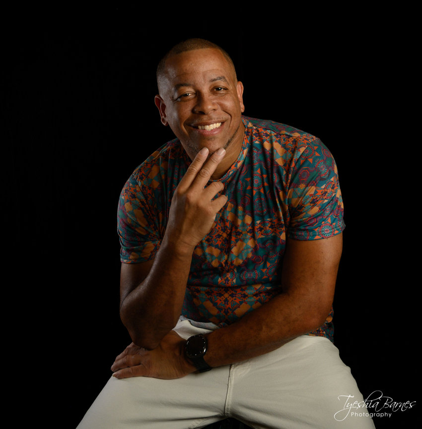 Studio headshot of young professional with black background.