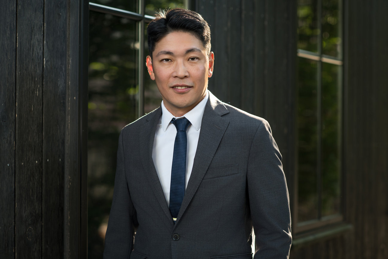 Professional headshot of a male executive in a gray suit and blue tie, photographed outdoors in Dublin Ohio by branding photographer Claudine Kosier