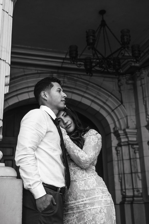 Black and white portrait of a couple embracing under an arch