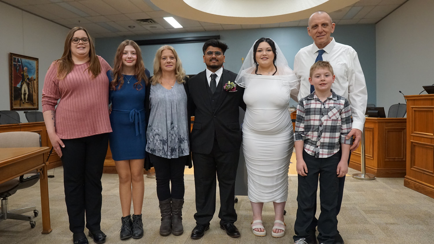 Wedding couple posing with family in a ceremony room