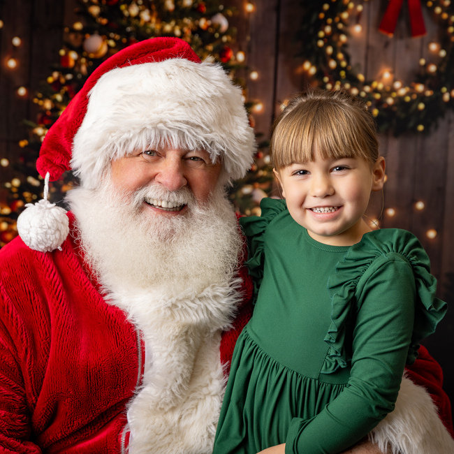 Santa smiles beside a child during a past session
